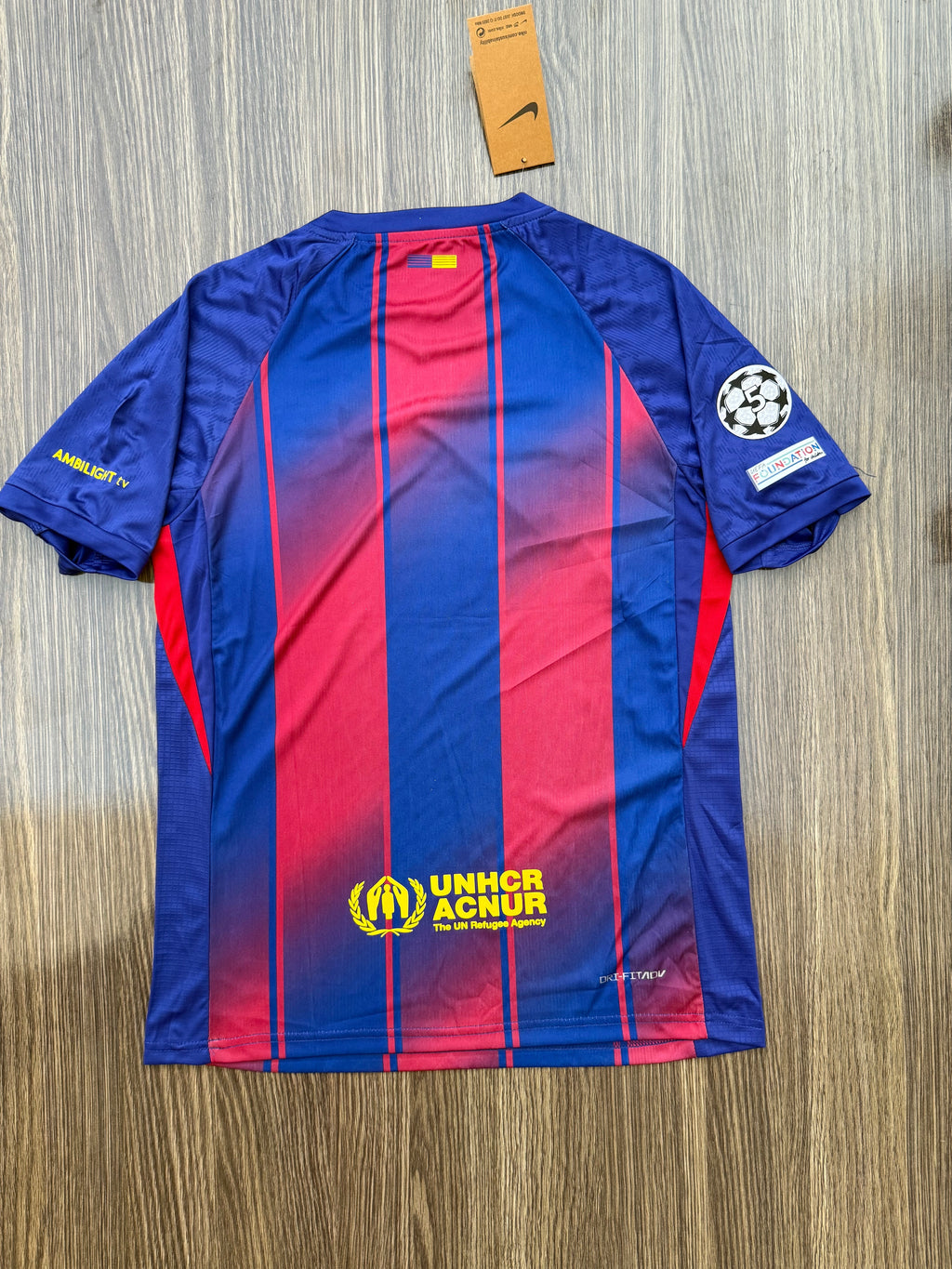 Blue and red sports jersey with UNHCR logo on a wooden surface