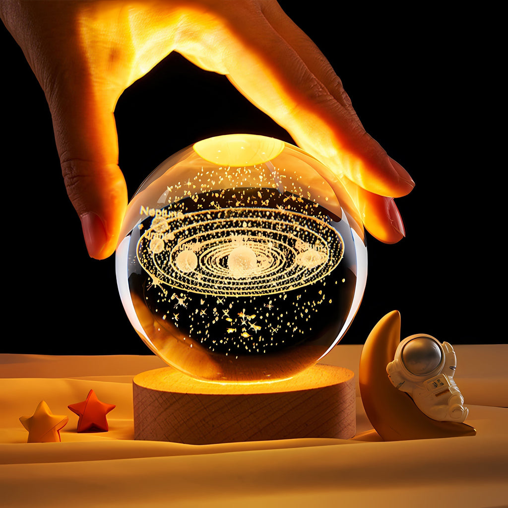 Crystal ball with solar system model held by a hand on a dark background