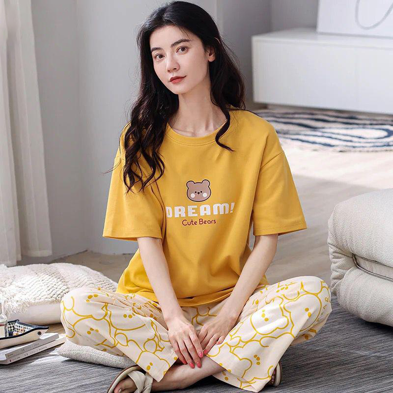 Woman wearing a yellow t-shirt with a bear graphic and text, sitting on a couch.