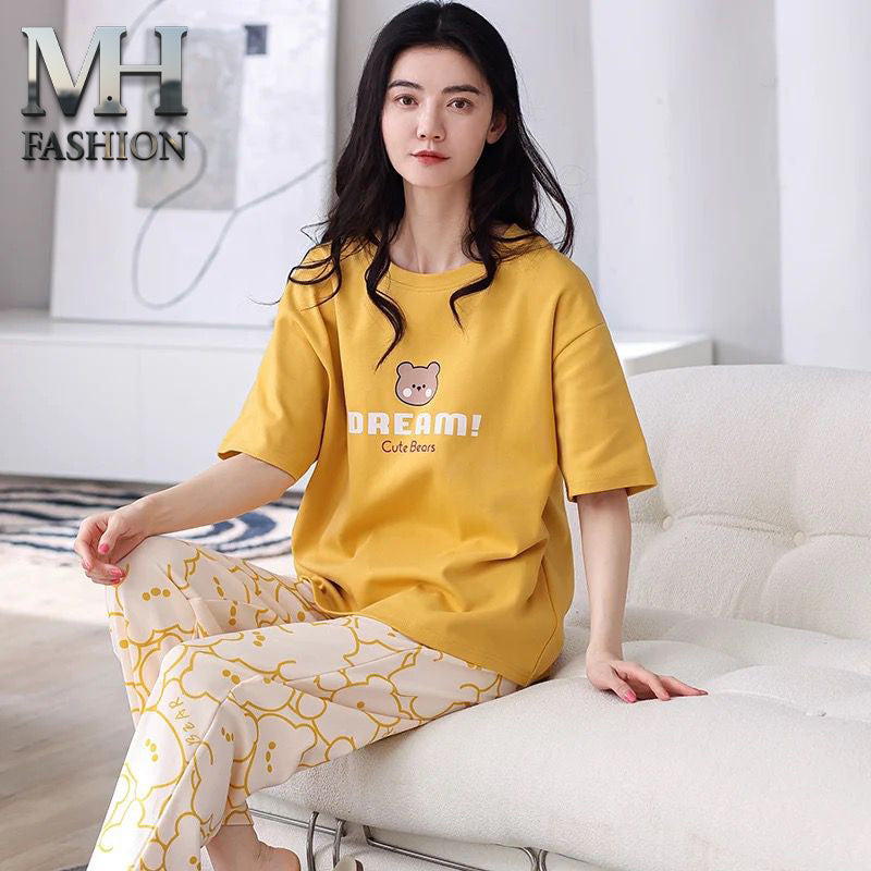 Woman wearing a yellow outfit with a teddy bear design, sitting on a white couch.