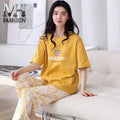 Woman wearing a yellow outfit with a teddy bear design, sitting on a white couch.