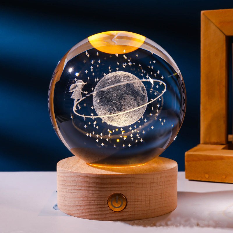 Glass ball with celestial design on a wooden base against a dark blue background