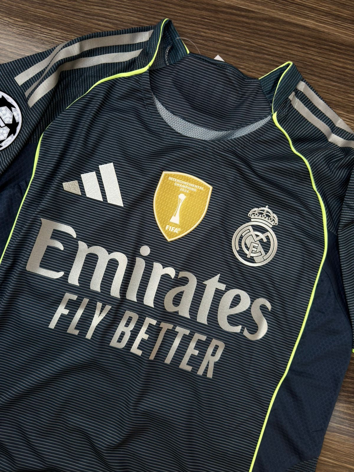 Real Madrid sports jersey with Emirates logo on a wooden surface