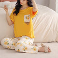 Woman wearing a yellow top and floral pants sitting on a couch.