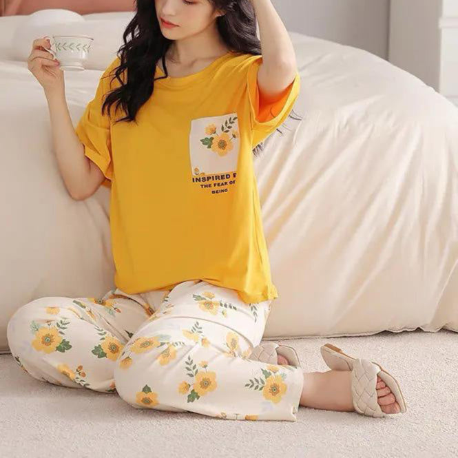 Woman wearing a yellow top and floral pants sitting on a couch.