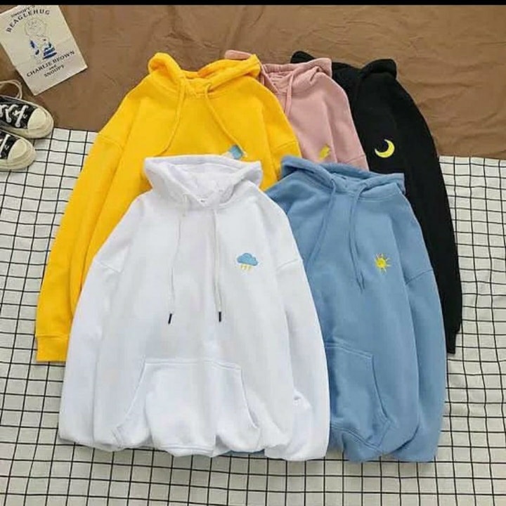 Five hoodies in yellow, white, blue, pink, and black on a checkered surface.