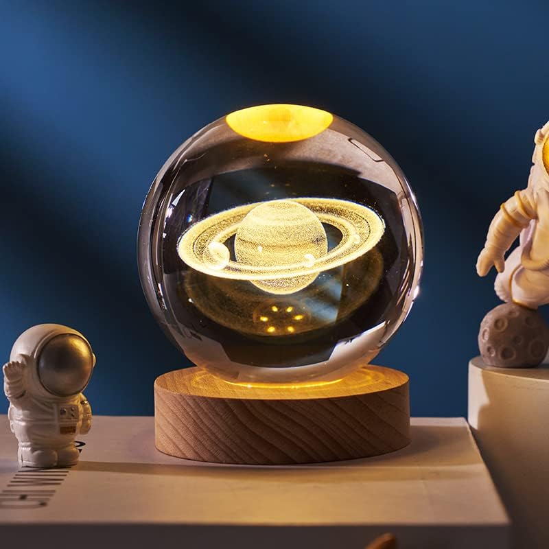 Glass sphere with Saturn model on a wooden base against a dark blue background