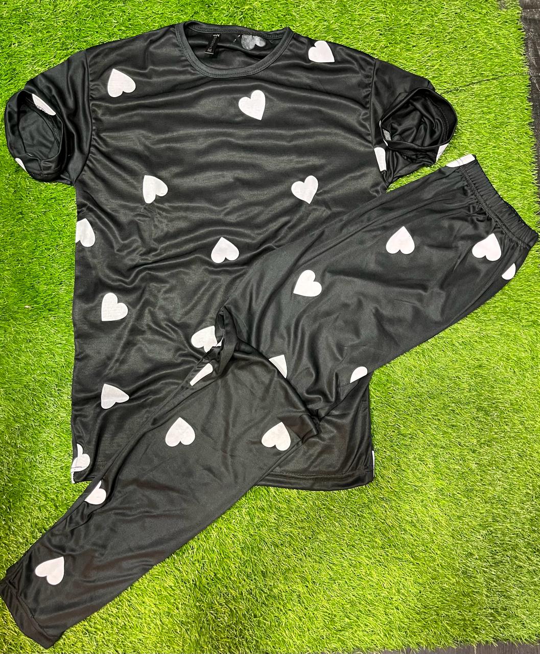 Black pajama set with white heart patterns on a green surface