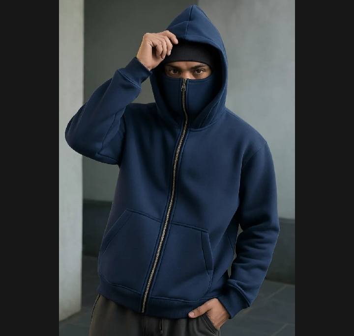 Person wearing a blue hoodie with a zipper, standing against a plain background