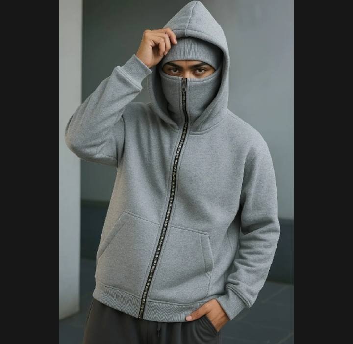 Person wearing a gray hoodie with a zipper, standing against a neutral background