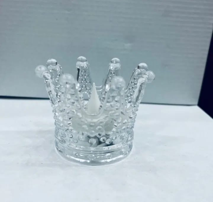 Clear glass crown-shaped object on a white surface with a blurred background
