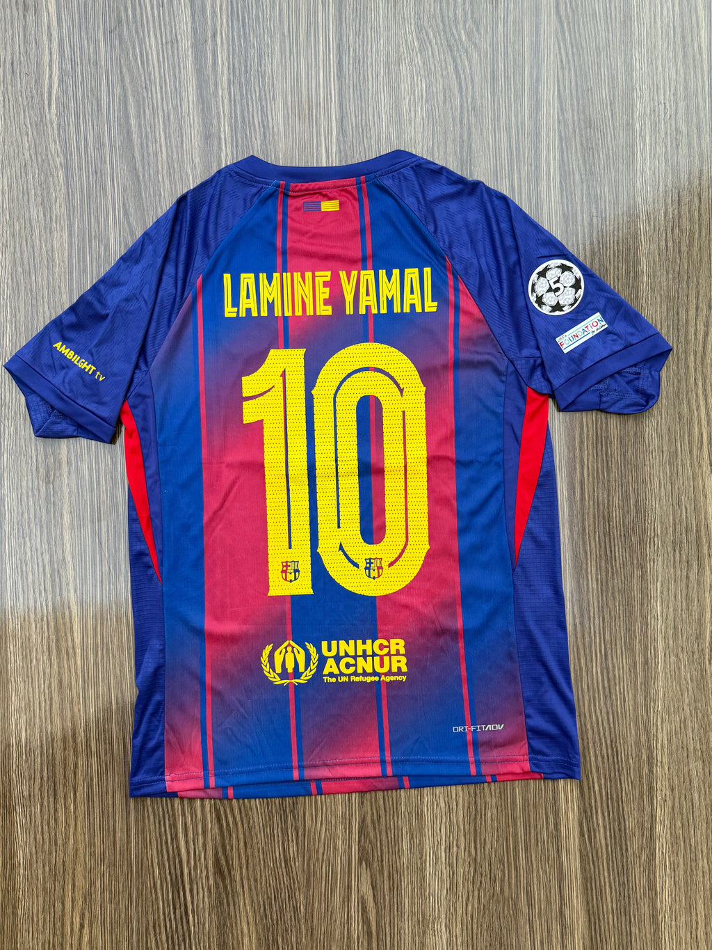 Blue and red sports jersey with number 10 and name 'Lamine Yamal' on a wooden surface