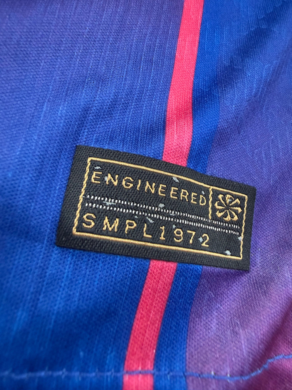Close-up of a 'Engineered' label on a blue and pink fabric background
