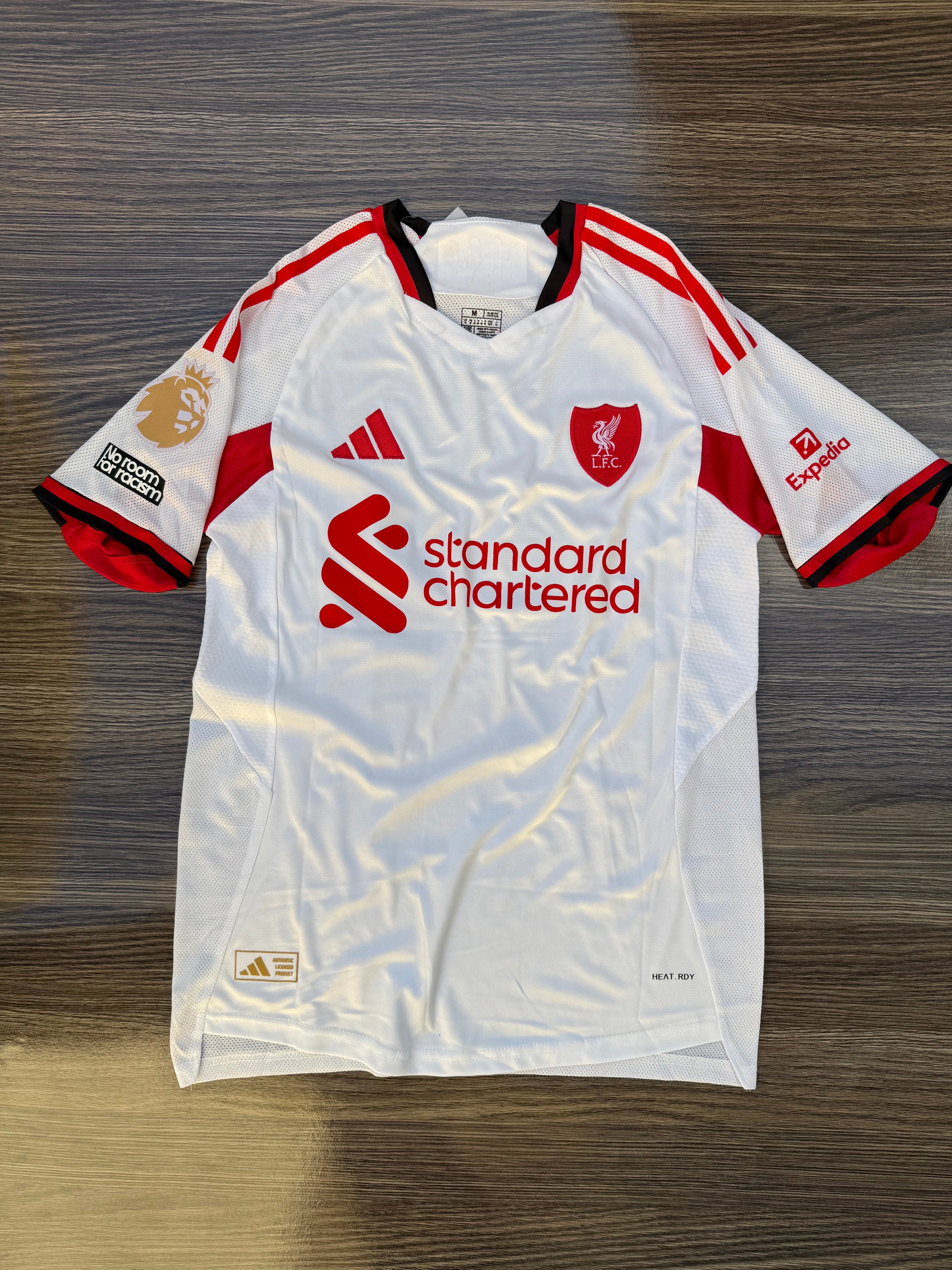 White sports jersey with red accents and branding on a wooden surface