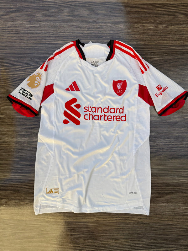 White sports jersey with red accents and branding on a wooden surface