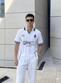 Man wearing a white sports outfit with 'game' logo in front of a modern building.