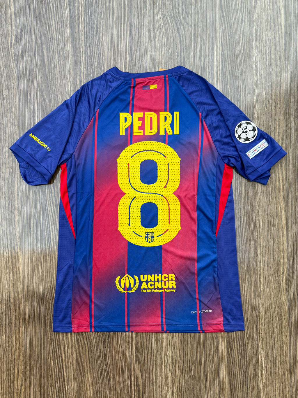 Blue and red sports jersey with 'Pedri' and number '8' on a wooden surface