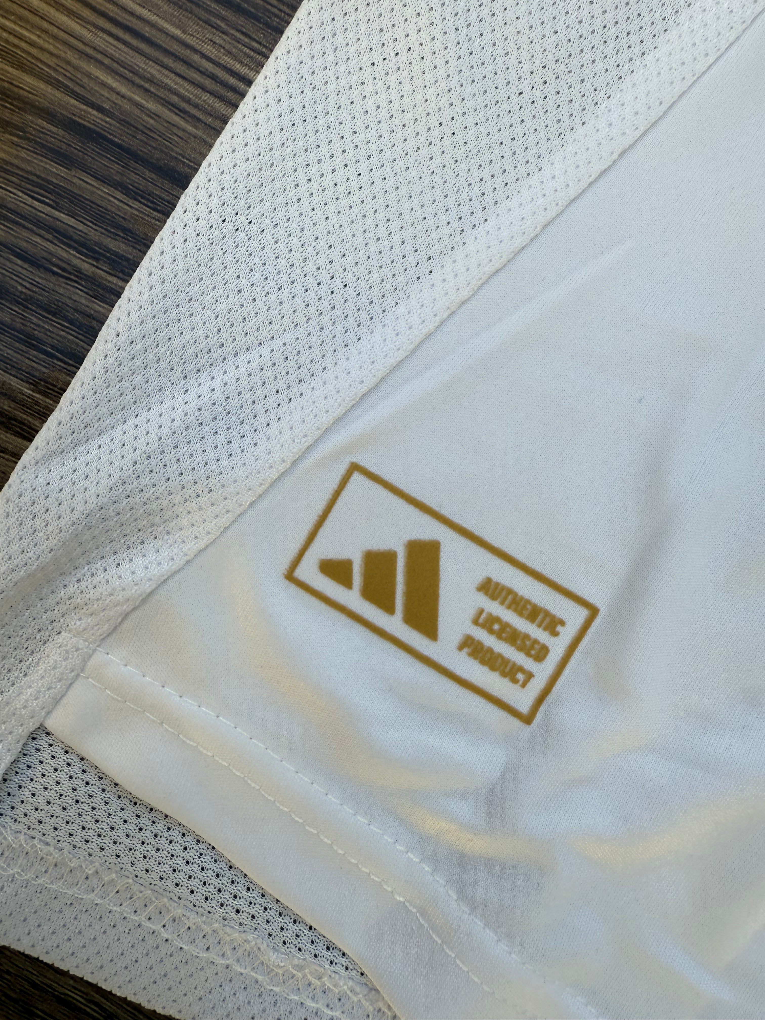 White fabric with a gold Adidas logo and text on a wooden surface