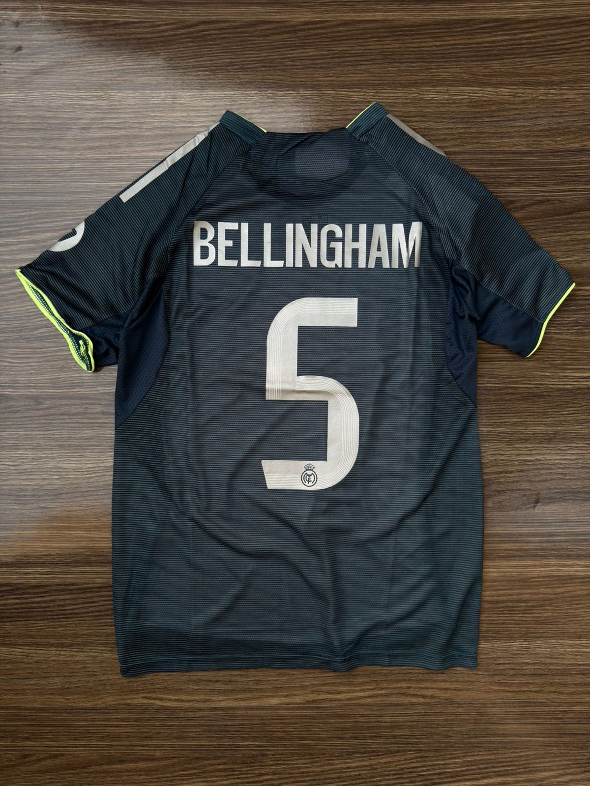 Black sports jersey with 'Bellingham' and number '5' on a wooden surface