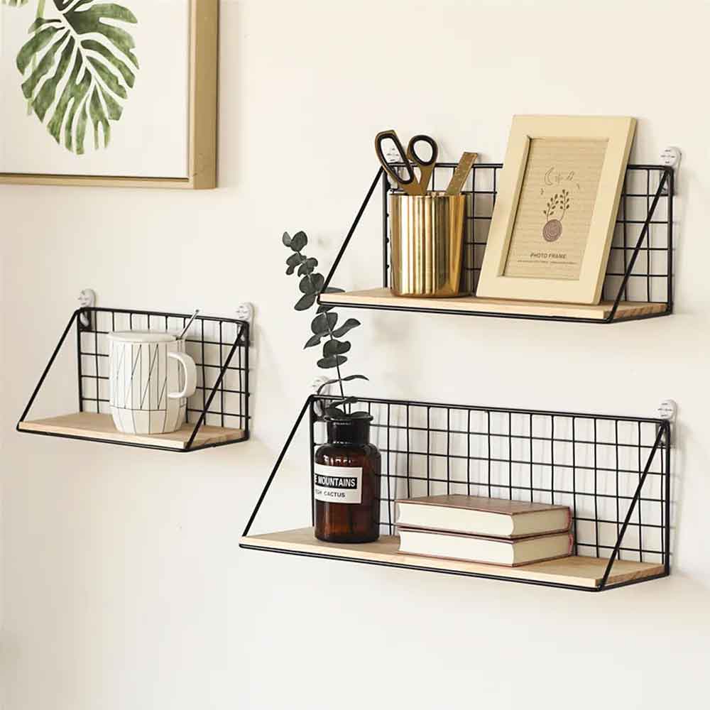 Set of wall-mounted wire shelves with books, a mug, and decorative items on a white wall.