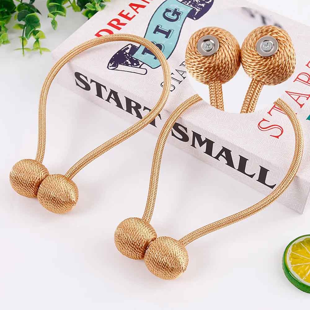 Gold hair ties with decorative beads on a white surface with a motivational book in the background.