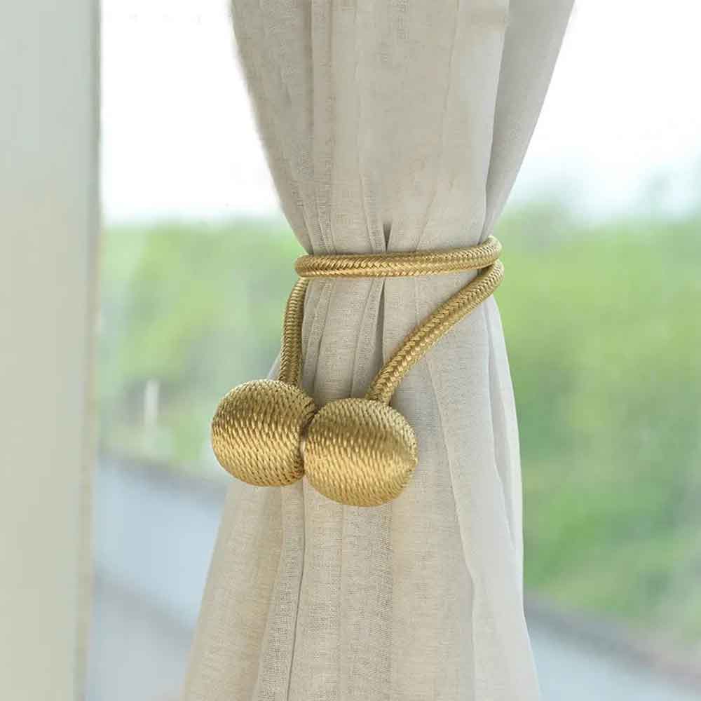 Gold curtain tieback with beige curtains in front of a window