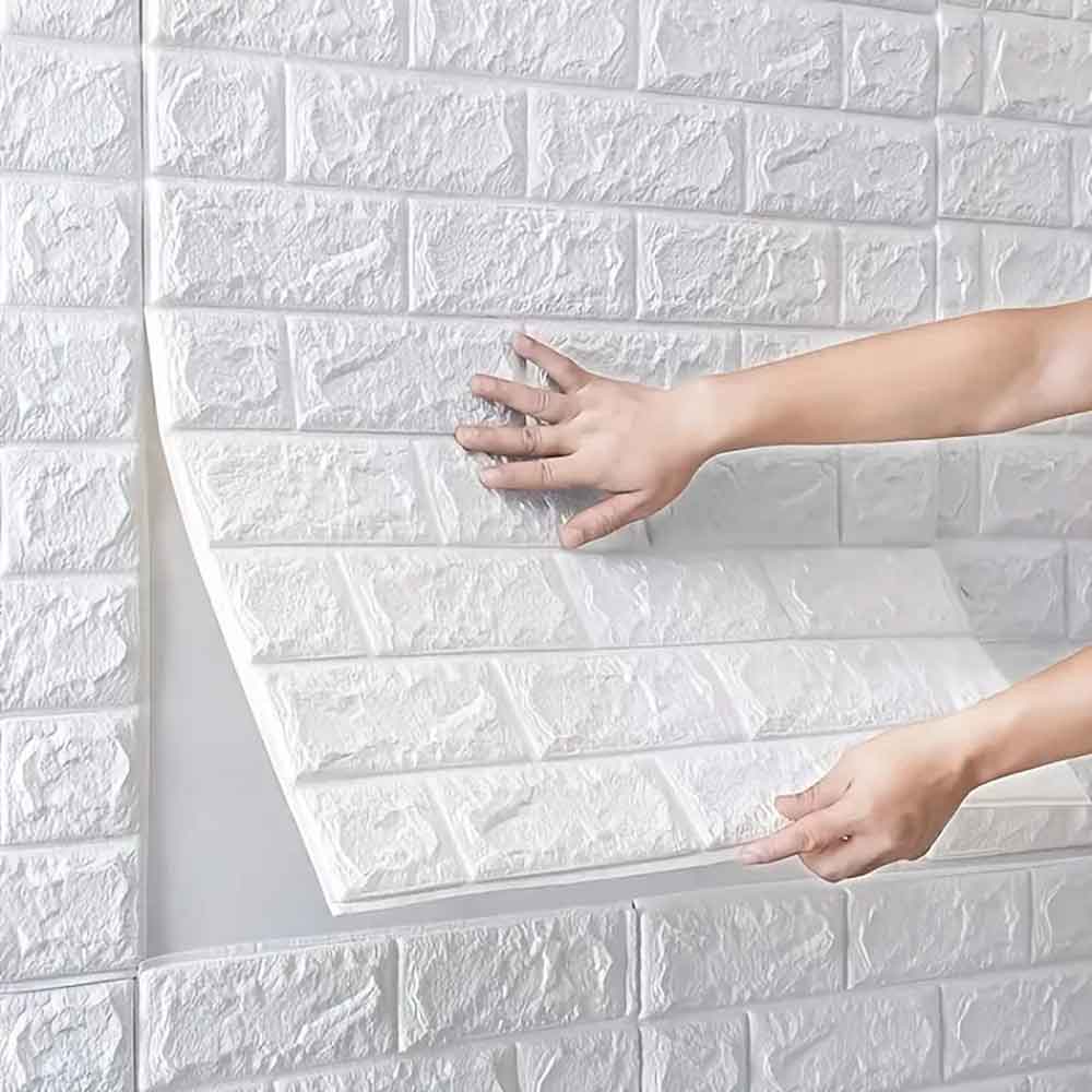 White brick-patterned wall panel being held by a person against a matching wall.