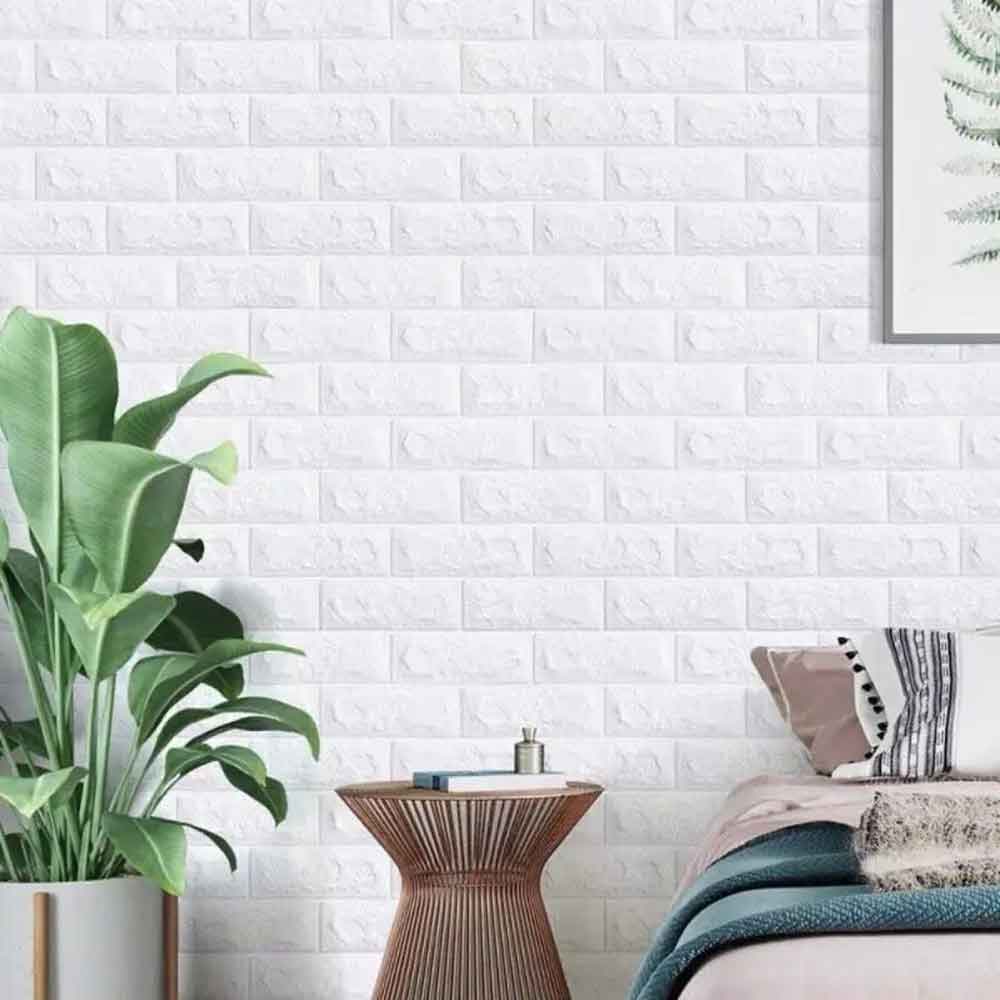 Room interior with a bed, side table, and plant against a white brick-patterned wall.