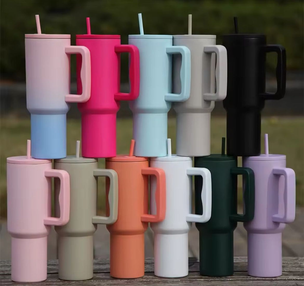Collection of colorful tumblers with handles and straws on a wooden surface.