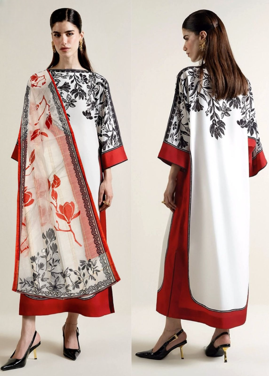 Woman wearing a white dress with red and black floral patterns, standing against a plain background.