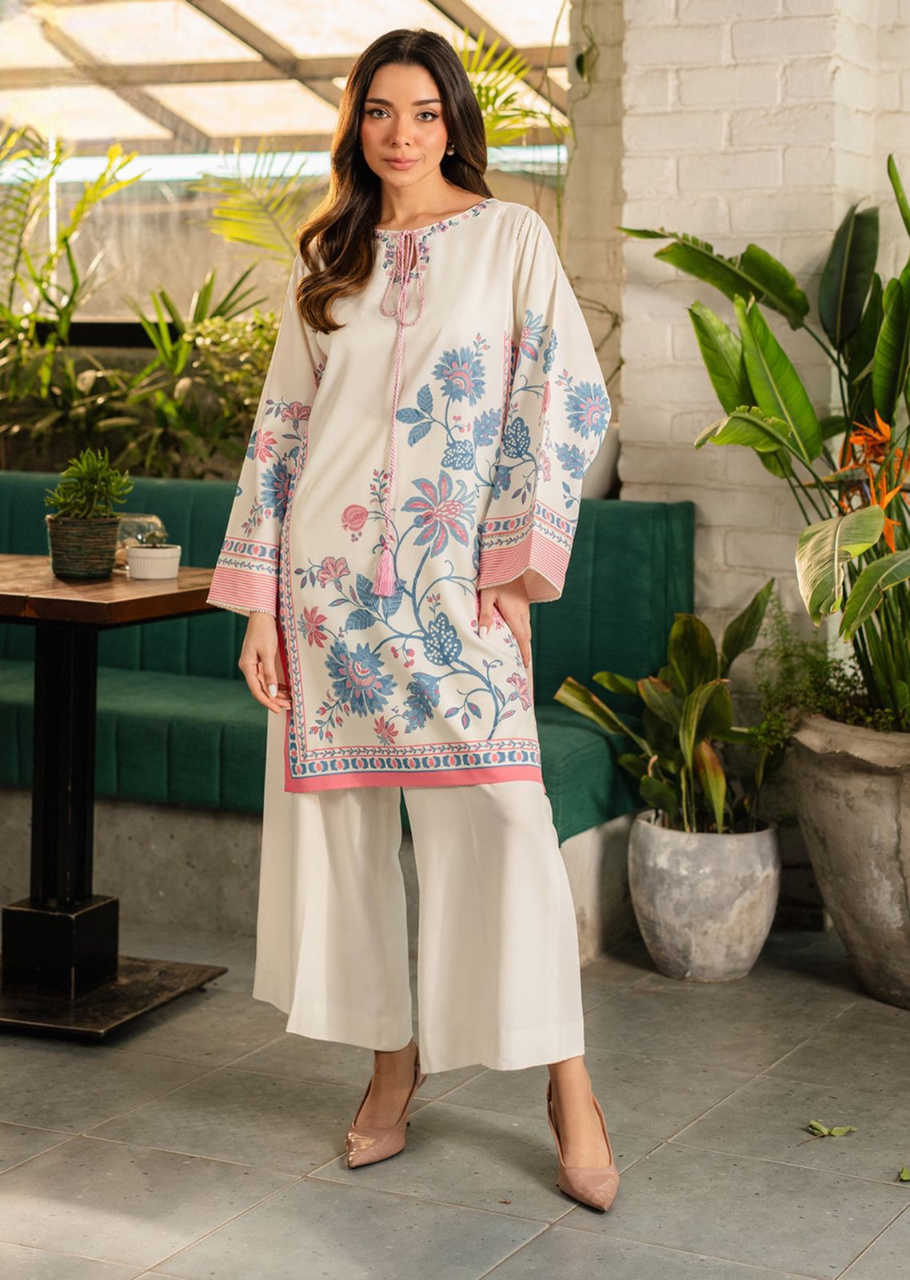 Woman wearing a floral embroidered outfit in an outdoor setting with plants and a table.