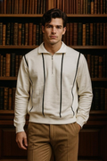 Man wearing a cream-colored sweater with black stripes in front of a bookshelf.