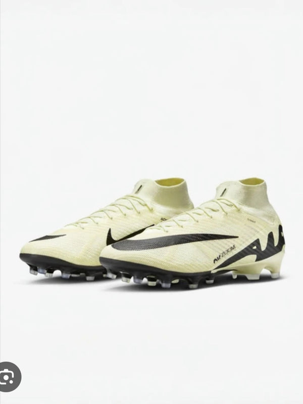 Pair of light-colored soccer cleats with a black swoosh logo on a white background