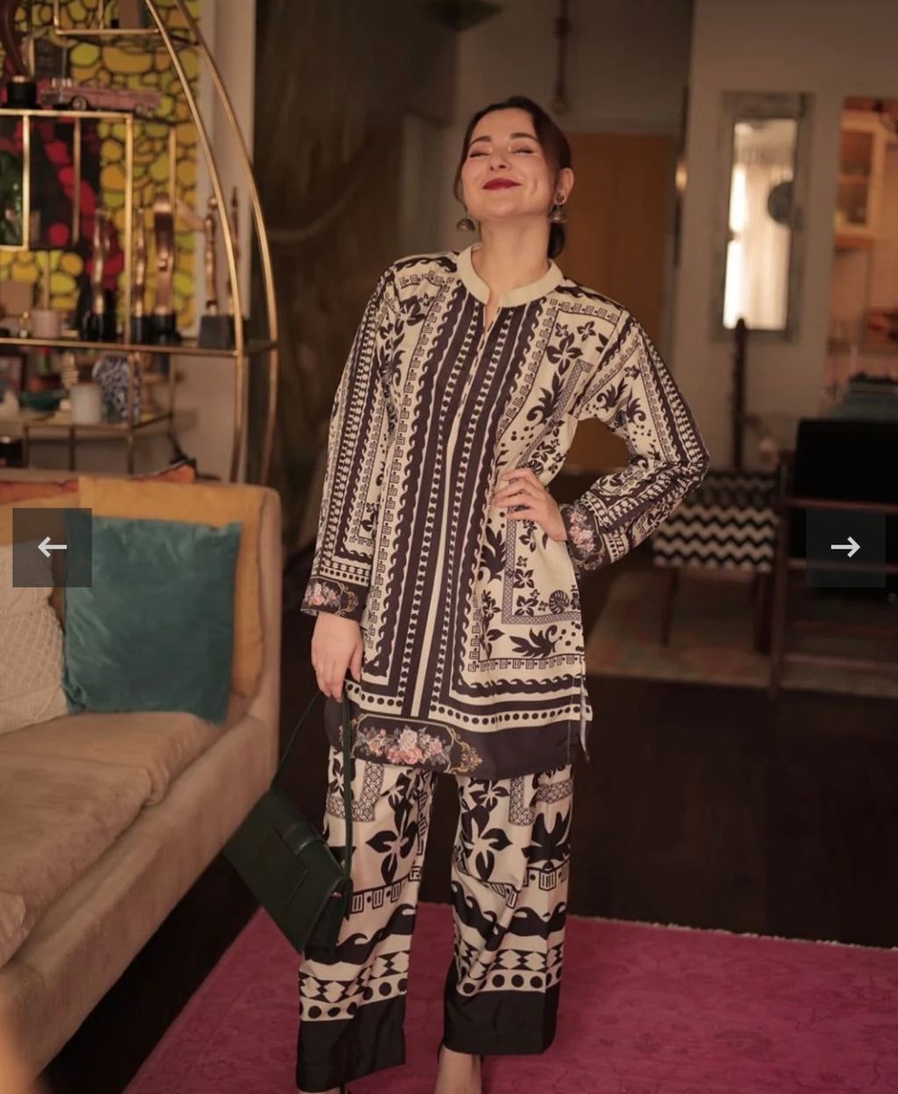Woman in a patterned outfit standing in a room with furniture and decor.