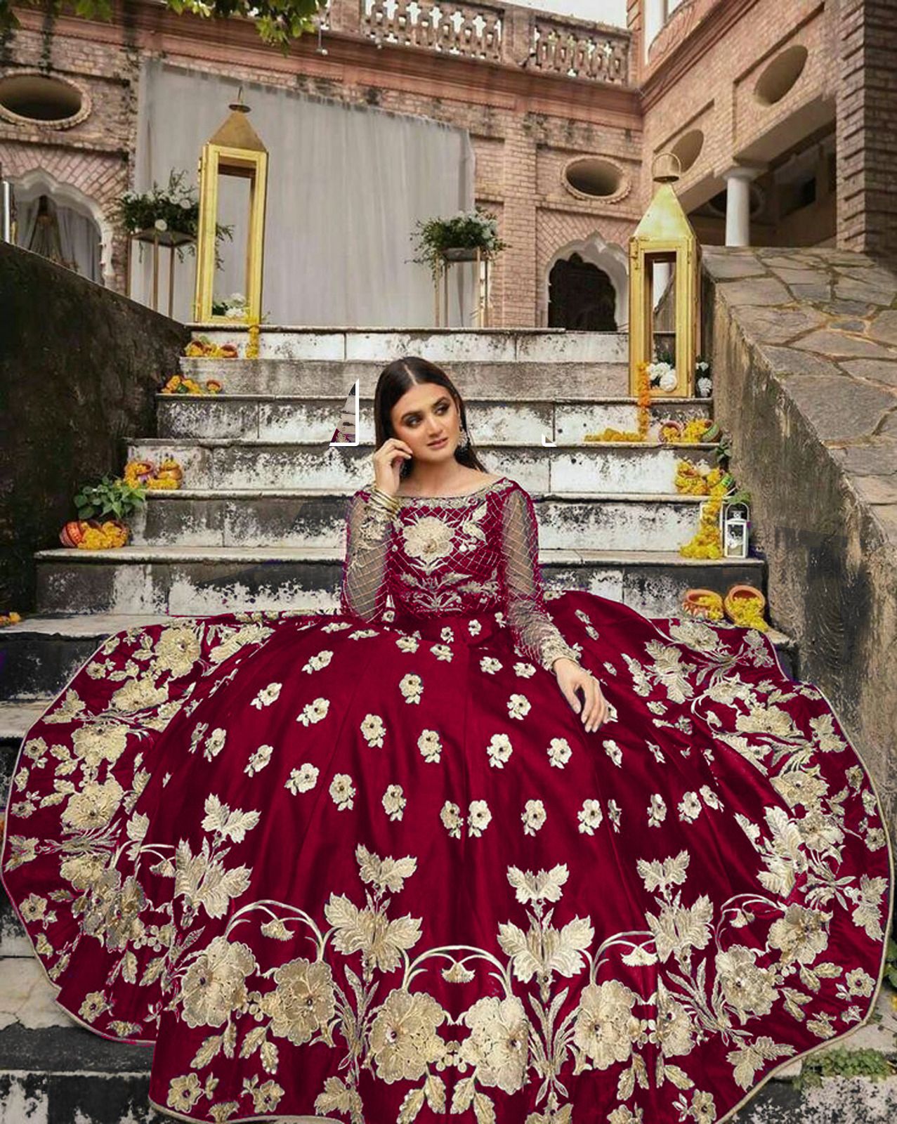 Woman in a red and gold embroidered dress sitting on steps with decorative elements.