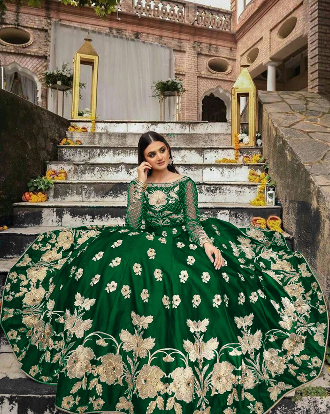 Woman in a green and white floral dress sitting on stone steps.