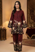 Woman wearing a maroon floral outfit in an indoor setting with decorative elements.
