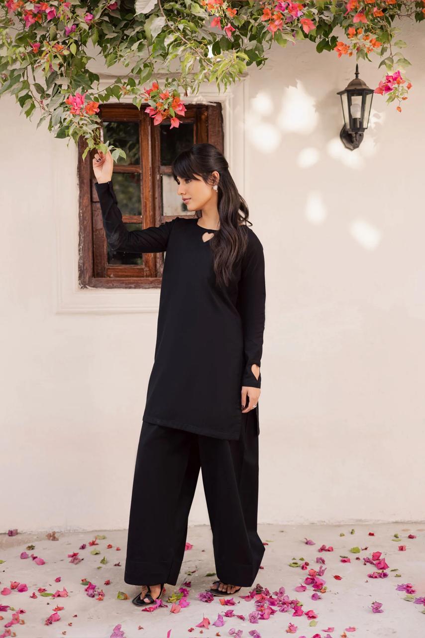 Woman in a black outfit standing in a decorated room with flowers and lights.