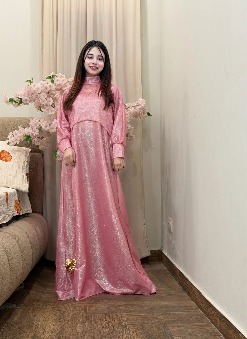 Woman in a pink dress standing in a room with a couch and decorative pillows.