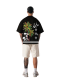 Person wearing a black t-shirt with colorful palm tree design on the back, standing against a white background.