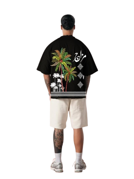 Person wearing a black t-shirt with colorful palm tree design on the back, standing against a white background.