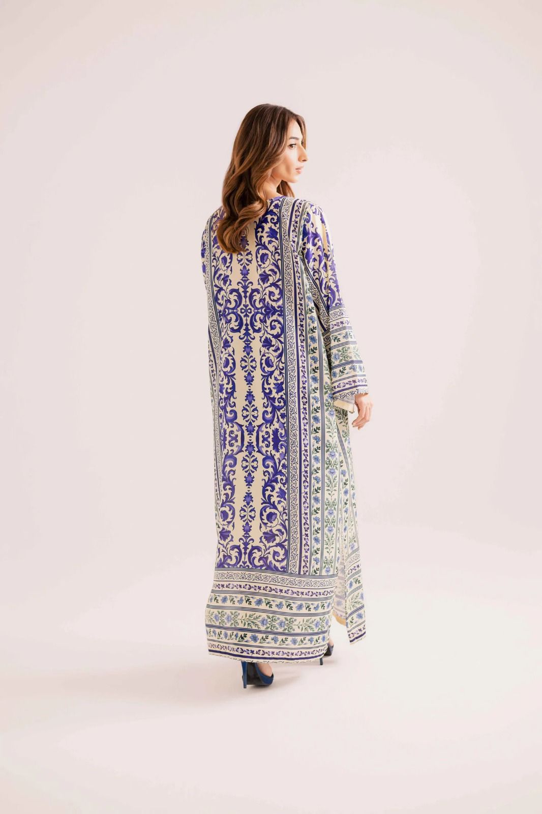 Woman wearing a long, patterned dress on a white background
