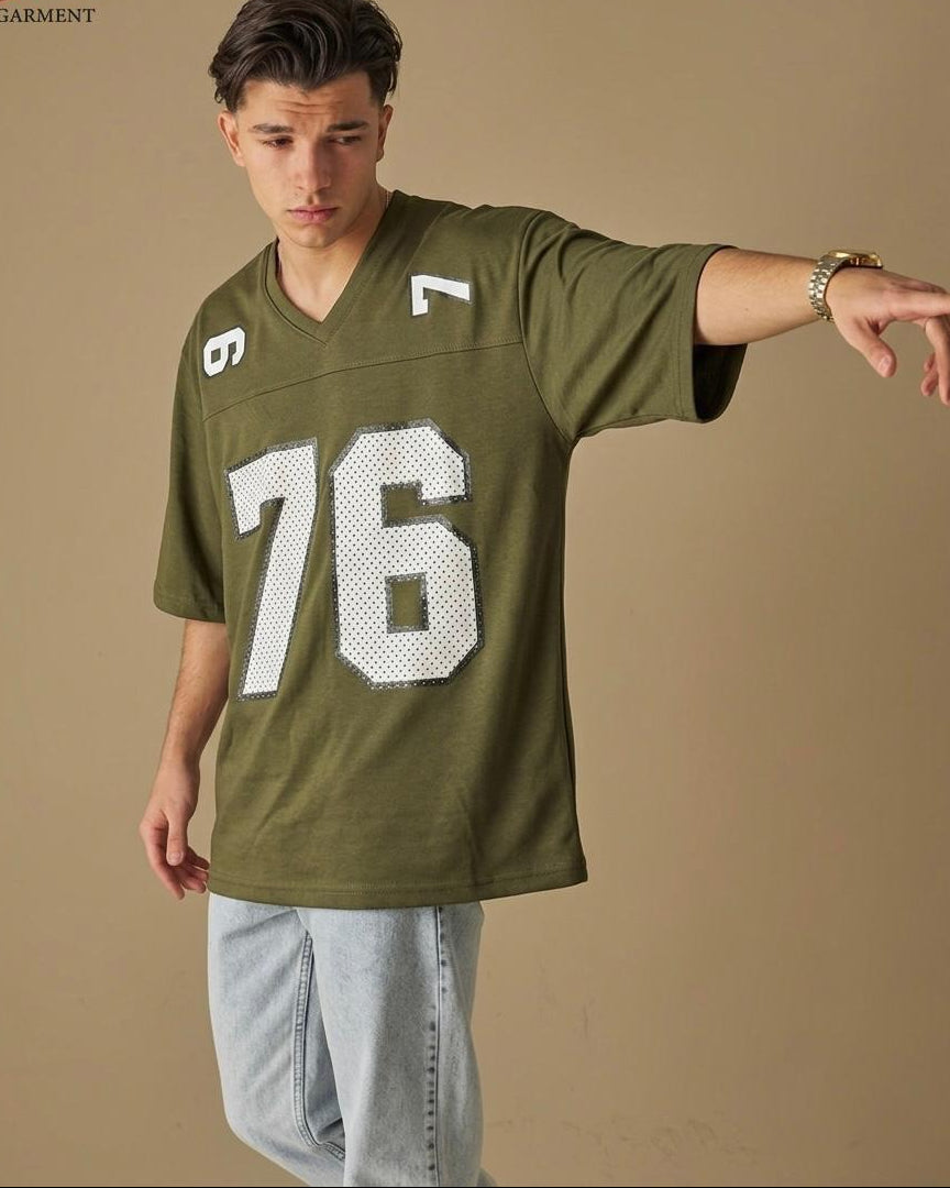 Man wearing a green sports jersey with numbers on a beige background
