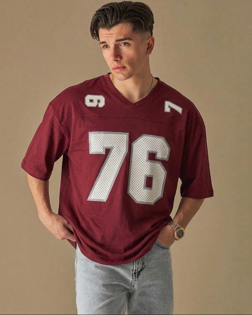 Man wearing a maroon sports jersey with the number 76 on a beige background