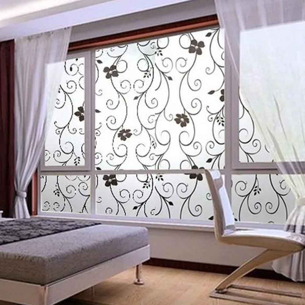 Decorative window film with floral pattern applied to a window in a room with a chair and bed.