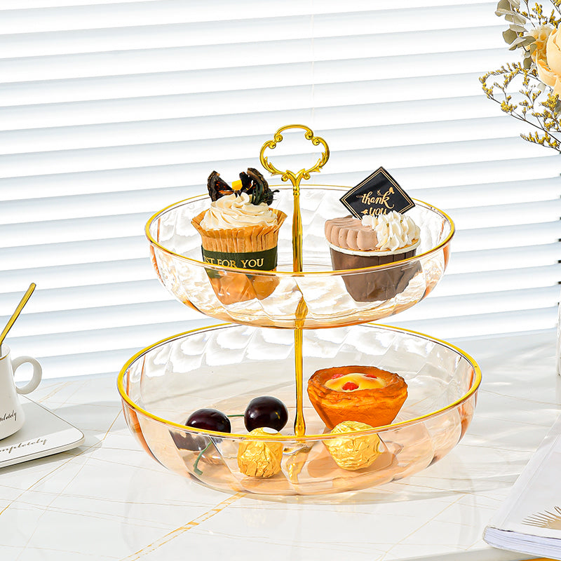 Two-tiered glass dessert stand with pastries on a white surface.