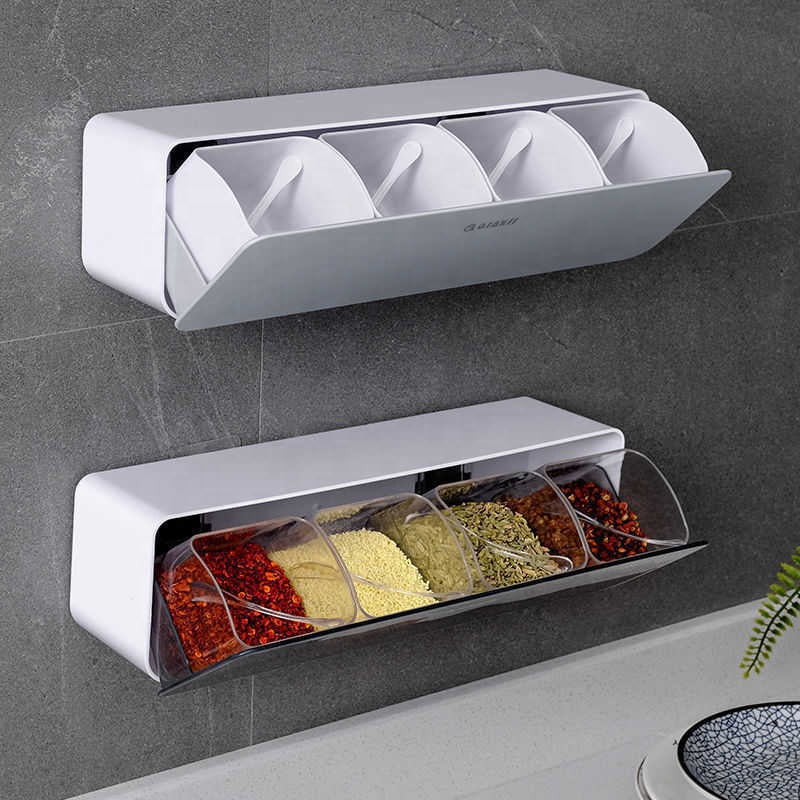 Wall-mounted spice rack with transparent compartments containing various spices on a kitchen counter.