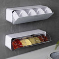 Wall-mounted spice rack with transparent compartments containing various spices on a kitchen counter.