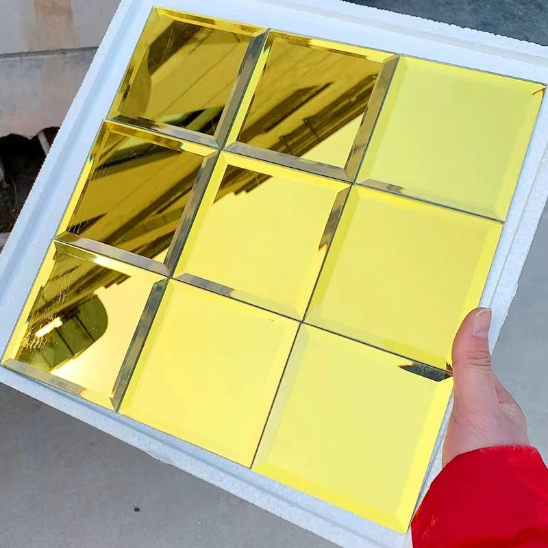 Gold mirror sheet held by a hand with a red sleeve on a neutral background
